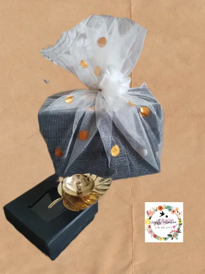 A simple yet elegant Diwali gift combo. This features a beautiful leaf-shaped brass diya, packaged in a sleek black box and wrapped in decorative white and gold-dotted netting, making it an ideal corporate or personal festive gift.