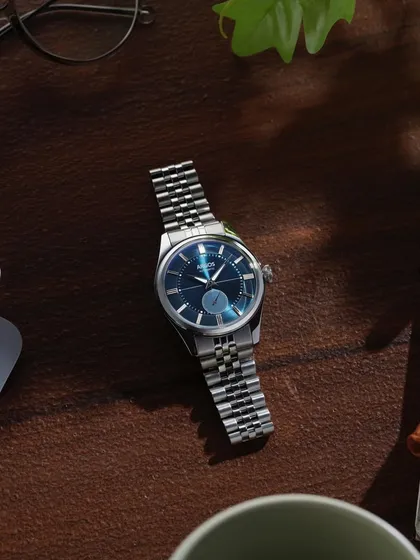 A lifestyle flat lay showing the Argos watch in a modern workspace. This contextualizes the product, showing who might wear it and how it fits into their daily life.