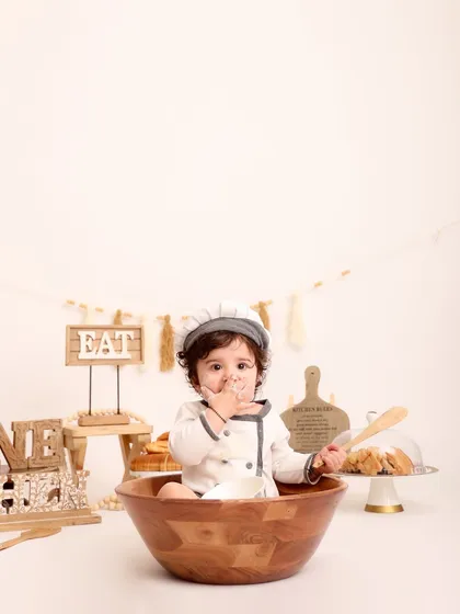With a little flour on his face, the baby chef tastes his "creation." This candid moment adds a touch of humor and authenticity to the themed photoshoot.