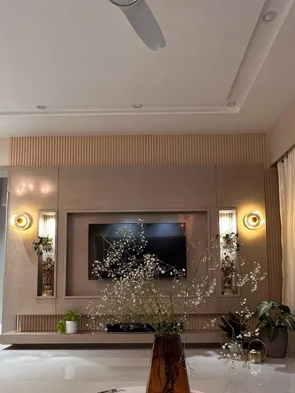 This TV unit design combines veneer with fluted panels for a textured, modern look. The wall-mounted lights in the niches add ambient lighting and highlight decorative items.