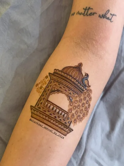 The beginning of a royal design, with a peacock with a flowing tail perched on a jharokha (balcony).