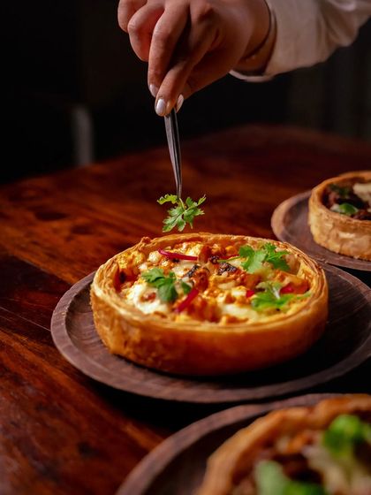 The final touch. A chef garnishes a Paneer Tikka Puffizza, a dish where nostalgia and magic are the key ingredients.