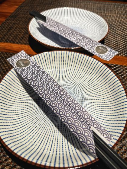 The simple elegance of our table setting, featuring traditional Japanese ceramic plates and chopsticks, awaits your arrival.