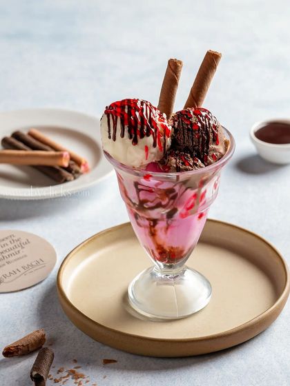 A classic tutti-frutti ice cream sundae with chocolate and strawberry sauce, topped with wafer sticks.