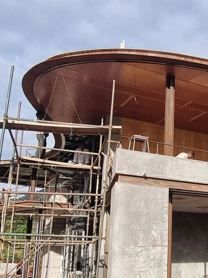 The curved steel and wood canopy of 'the hat' being meticulously assembled on site. This element is a defining feature of the design, and its construction required great skill and craftsmanship.