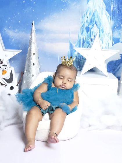 Even a sleeping princess fits perfectly in our Frozen theme. This photo shows the baby peacefully napping on a tiny white chair amidst the snowy, magical setting.