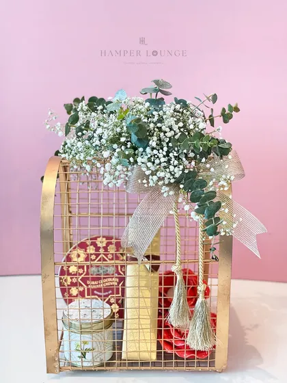 A unique bird-cage style metal basket makes this Eid hamper stand out. It’s filled with festive goodies and topped with a beautiful arrangement of baby's breath, offering a touch of whimsical elegance.