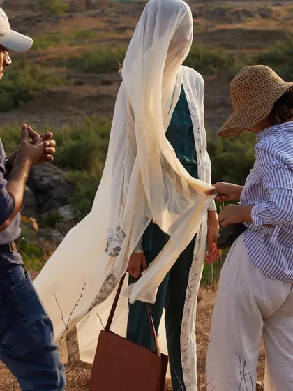 Styling is a crucial element of storytelling in fashion photography. This moment shows the stylist adjusting the fabric to create a sense of movement and grace, a small detail that has a big impact on the final image.