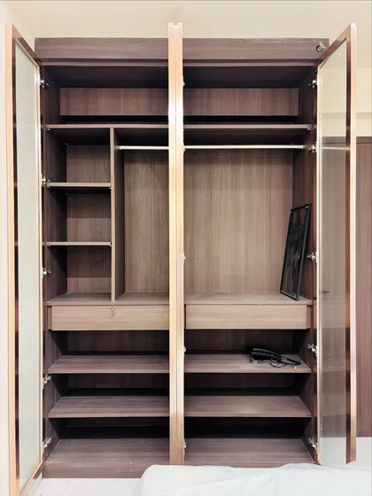 The interior of the glass-door wardrobe, showing the spacious layout with hanging rods, shelves, and drawers.