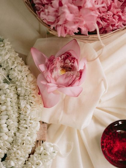 A single pink lotus, a symbol of purity and beauty, rests on soft white fabric. It's these small, thoughtful details that elevate the decor and add deeper meaning to the celebration.