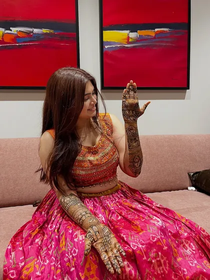 A lovely pose from a bride, giving a glimpse of her full-arm mehendi. The design is intricate and detailed, a true work of art for her special day.