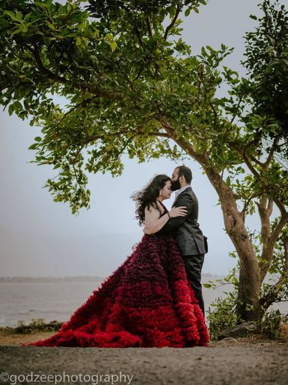 A romantic embrace under a tree. This ombre red and purple ruffled gown has a beautiful, dramatic train that adds a touch of passion to this pre-wedding portrait.