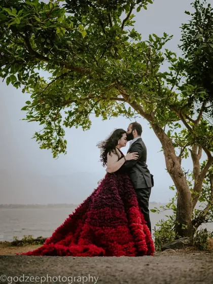 A romantic embrace under a tree. This ombre red and purple ruffled gown has a beautiful, dramatic train that adds a touch of passion to this pre-wedding portrait.