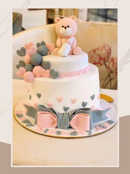 A lovely baby shower or first birthday cake in pink and grey, featuring a teddy bear and balloon accents.