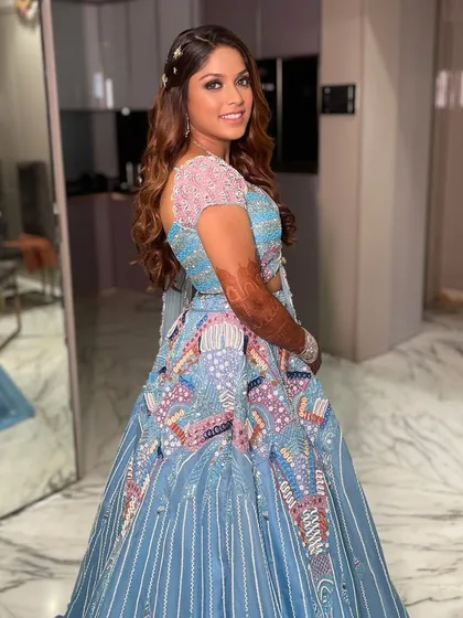 A vibrant and bold look for Shikha's carnival-themed Sangeet. The makeup features a pop of blue on the eyes to match her stunning Estilo Urvi Shah lehenga.