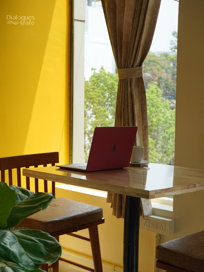 A laptop, a cup of coffee, and a view. This is the simple recipe for a productive day at my cafe, where the bright, yellow decor and natural light create a cheerful work environment.