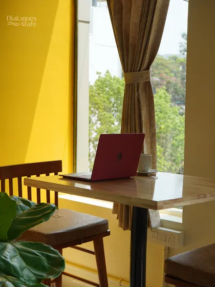 A laptop, a cup of coffee, and a view. This is the simple recipe for a productive day at my cafe, where the bright, yellow decor and natural light create a cheerful work environment.