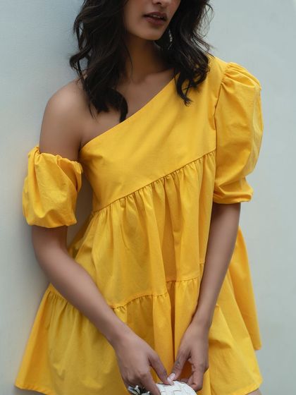 A close-up portrait focusing on the unique one-shoulder design of an Itgirl Love dress. This shot highlights the key features of the garment while maintaining a soft, fashionable feel.