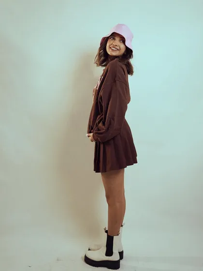 A full-length side profile of Diksha Rawat, showing the complete outfit with a pleated skirt and platform boots. This provides a clear look at the head-to-toe styling.