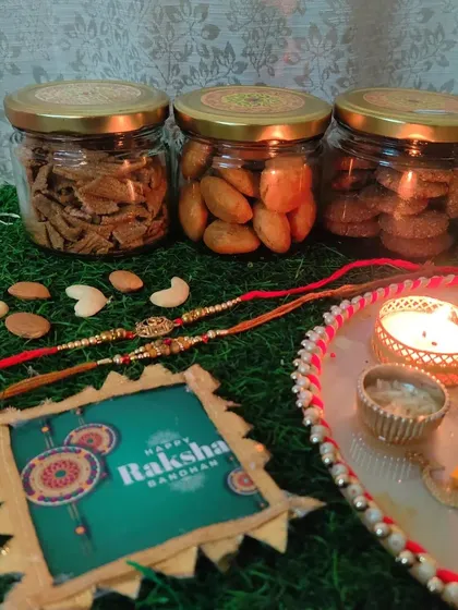 A premium Rakhi hamper for your beloved brother or sister. This one includes airtight glass jars filled with healthy Ragi Chips, Khasta Kachori, and Ragi Cookies, along with a beautiful rakhi.