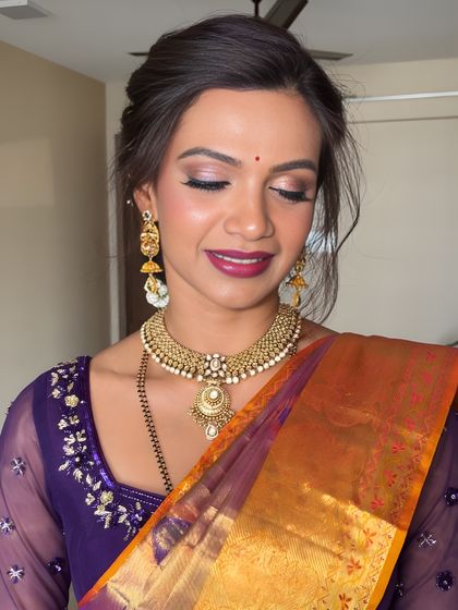 A close-up of the eye makeup, showing a beautiful blend of shimmering lilac and deeper tones that make her eyes pop. The skin is kept fresh and dewy.