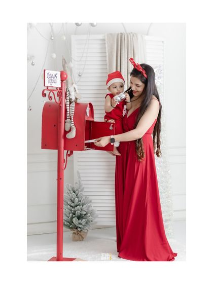 A mother holds her baby up to the Santa mailbox in this sweet Christmas portrait.