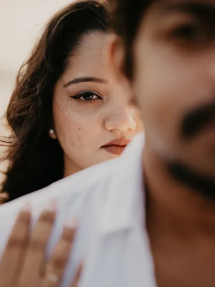 An artistic and intimate close-up, with the bride's intense gaze visible just over the groom's shoulder.