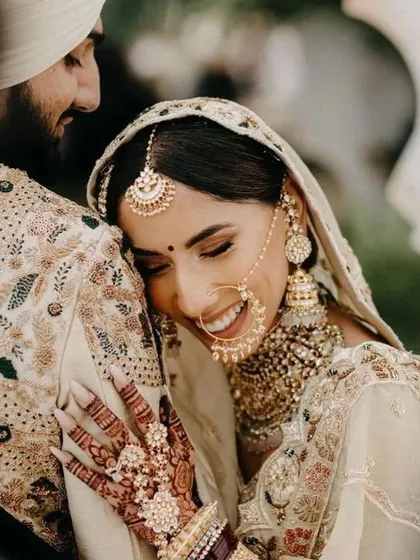We believe your wedding photos should be full of joy, and your outfits should match that feeling. This couple is coordinated in beautiful ivory and cream tones. The bride's lehenga features delicate embroidery, complemented by the groom's matching sherwani, creating a soft, elegant, and modern wedding look.