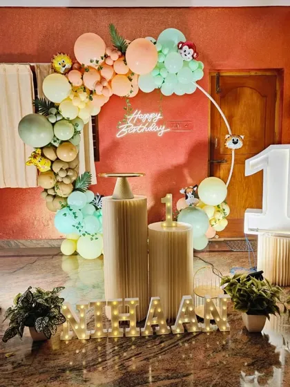 A clear shot of the home jungle party setup for Nihaan, showing the cake stands and light-up number '1'.