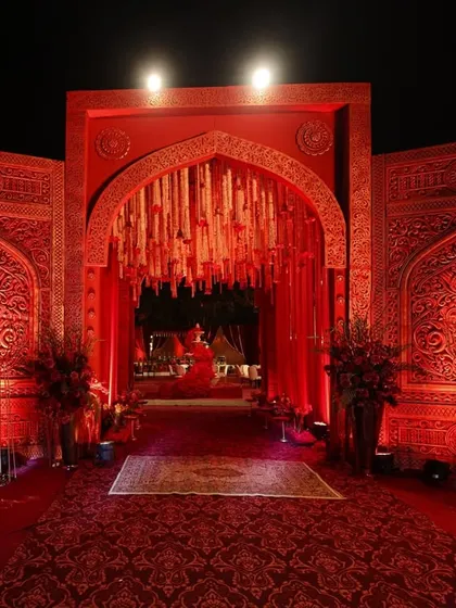 The entrance to a celebration should feel like stepping into another world. I used intricately carved crimson panels and a dramatic arch to create a grand, regal welcome for this wedding.