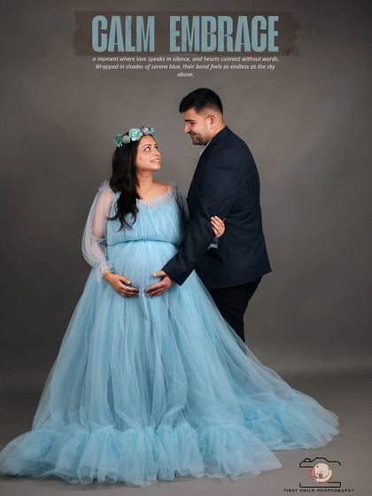 A beautiful studio portrait of an expecting couple. The mother-to-be wears a flowing light blue gown and a floral crown, while her partner stands beside her, creating a calm and loving image.