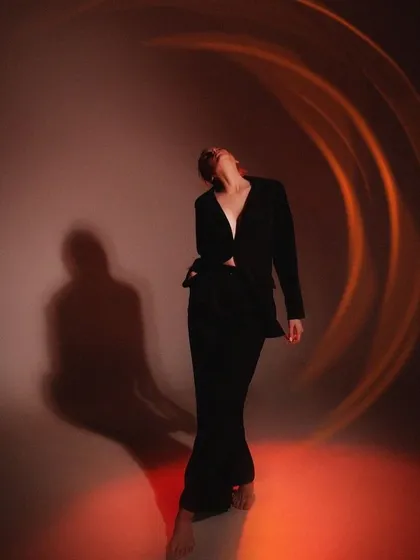 Titled 'Paradigm Shift,' this personal series shot captures a mood of introspection and change. The dramatic lighting with circular flares and the model's pose in a simple black suit create a powerful, artistic, and cinematic image.