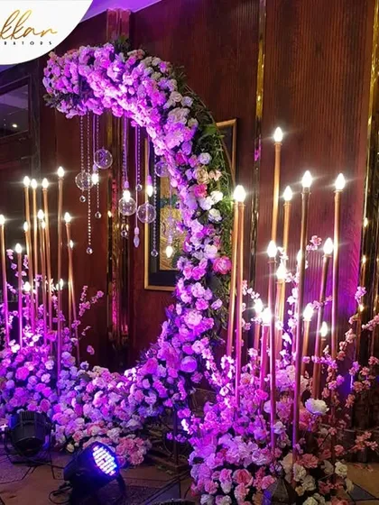 A unique photo opportunity I designed for a Sangeet. A crescent moon-shaped floral installation with hanging crystal drops and candle-lit pillars creates a magical and romantic spot.