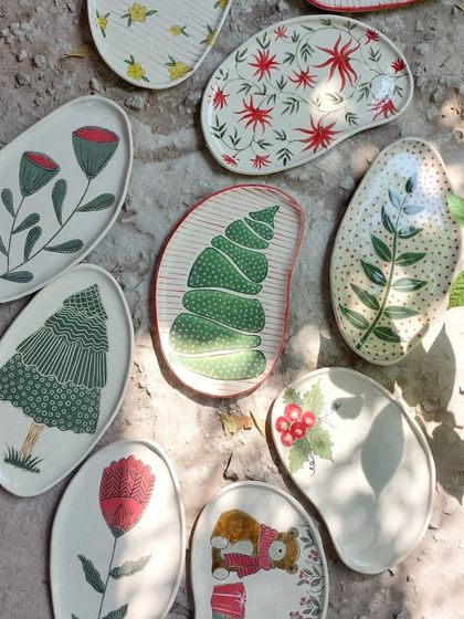 A collection of my hand-painted platters, featuring a variety of festive and floral designs. Each one is a unique piece of functional art, perfect for serving or display.