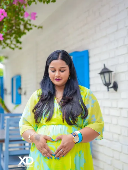 A quiet moment of reflection for the mother-to-be, her hands forming a heart on her belly.