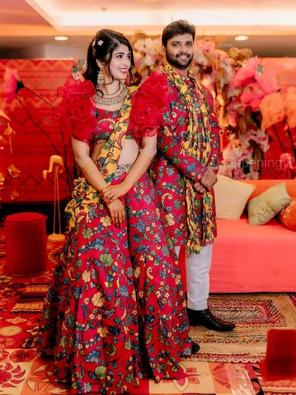 The couple posing for a photo at their Mehendi. The bright, floral decor we designed created a picture-perfect setting.