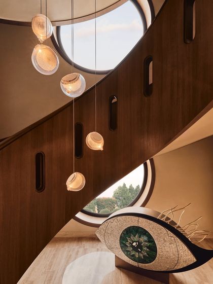 The base of the spiral staircase, featuring a large, eye-shaped art installation. This shows how we integrate bold, statement art pieces into the core architecture of a home.
