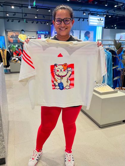 A customer proudly displaying her custom Adidas T-shirt featuring a Japanese Maneki-neko (beckoning cat) design for good luck.