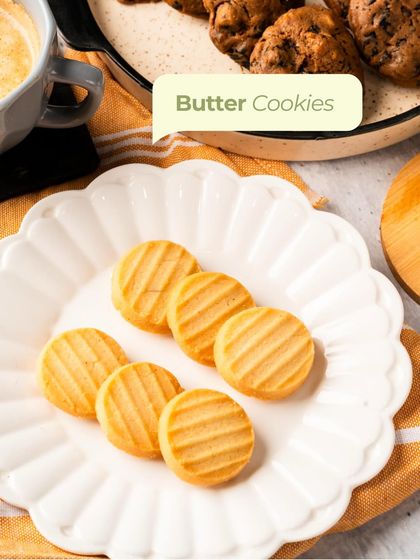 Simple, elegant Butter Cookies arranged on a fluted white plate. These melt-in-your-mouth treats are pure comfort, baked to golden perfection.