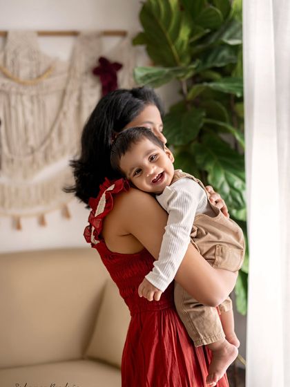 A mother holds her smiling son, who is resting his head on her shoulder. This is a simple, tender moment that speaks volumes about their bond.