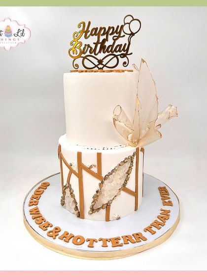"Older, wiser & hotter than ever." A chic two-tiered birthday cake with geode details and a delicate wafer paper sail.