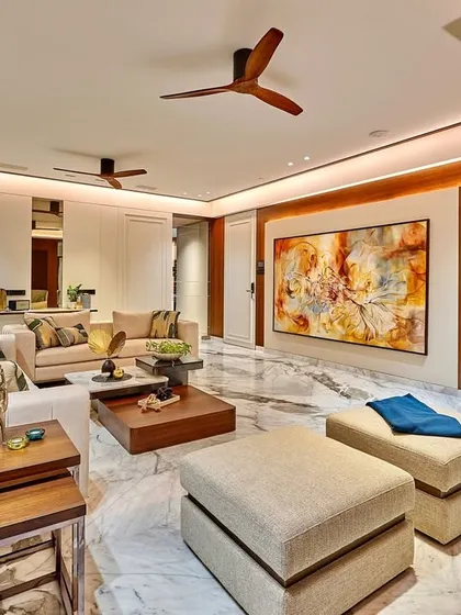 A full view of the living room, showing the harmony between different elements. The abstract art, backlit onyx panel, and mix of wooden and upholstered furniture come together to create a cohesive and luxurious space.