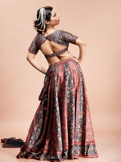 A full-length shot of a model showing the back and flow of her printed lehenga.