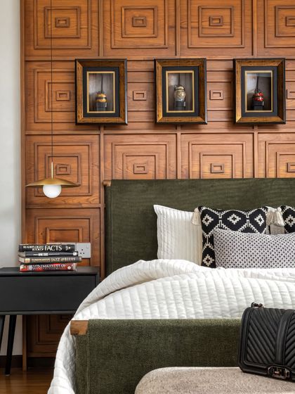 This guest bedroom features a statement wall of carved wood panels, adding incredible warmth and texture. The framed artifacts above the bed are from the client's collection, making the space personal.