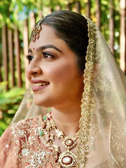 A close-up profile shot. You can see the delicate details of her makeup and the soft glow on her skin, framed by the beautiful sheer dupatta.