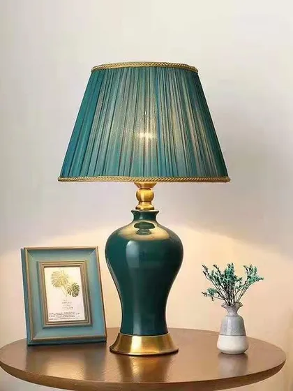 The deep green ceramic base and matching pleated shade give this table lamp a rich, cohesive look. The gold-finished bottom adds a touch of warmth, making it a beautiful accent for a bedroom or living room.