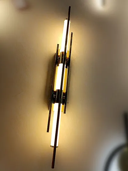 An art deco-inspired wall sconce with vertical light tubes and a metallic frame. This piece adds a touch of vintage glamour.