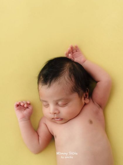 A minimalist shot of a sleeping newborn on a simple yellow backdrop.