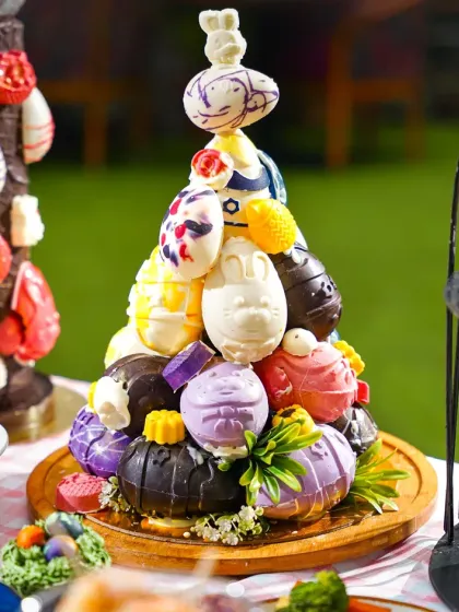 An impressive chocolate egg tower, intricately decorated with smaller bunnies and eggs, as a centerpiece for an Easter feast. This shot showcases high-level pastry artistry.
