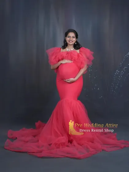 Celebrate your silhouette with this stunning red mermaid gown, designed to elegantly highlight your baby bump. The ruffled off-shoulder neckline and tulle train add a touch of glamour, making it perfect for a classic studio maternity session.